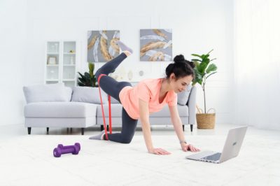 the girl trains at home online with elastic bands for fitness online home training for a woman with a laptop sports at home under quarantine 141188 5407